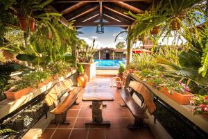 a patio with benches and potted plants and a table at Hosteria del Prado in Salta