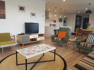 a living room with chairs and a tv and a table at House In The Heights in Taupo