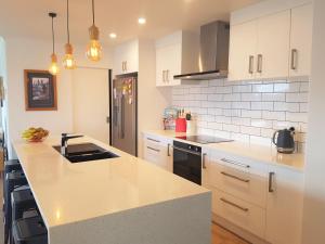 cocina con armarios blancos y encimera en House In The Heights, en Taupo