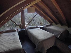 a room with two beds and a large window at La Patagonia Secreta in Villa Pehuenia