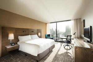 a hotel room with a bed and a desk and a television at Pan Pacific Melbourne in Melbourne