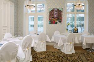 a dining room with white tables and chairs and windows at Annas Hotell in Kristianstad