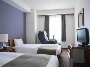 a hotel room with two beds and a television at Hotel Abest Nagano Ekimae in Nagano