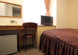 a hotel room with a bed and a desk with a television at Hotel Trend Funabashi in Funabashi