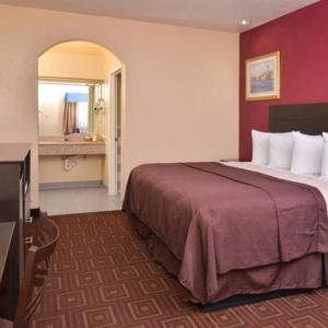 a hotel room with a large bed and a television at Americas Best Value Inn-Baytown in Baytown