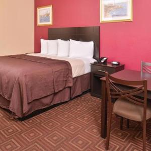 a hotel room with a bed and a table and a chair at Americas Best Value Inn-Baytown in Baytown