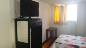 a bedroom with a television on a dresser with a bed at Hotel Ventura in Riobamba