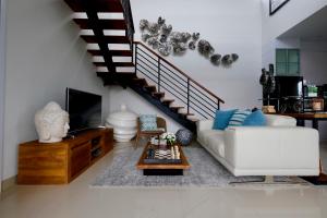 a living room with a white couch and a staircase at Villa Arusha Jogja in Sleman