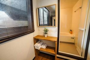 a bathroom with a mirror and a sink and a tub at Hotel Villa Hakuba in Hakuba
