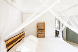 una camera da letto con un letto bianco con tende bianche di The Cottage Bentota a Bentota