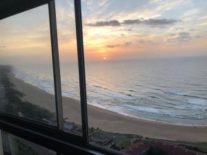 uma vista para o oceano a partir de uma janela de uma praia em Hightide Apartment em Amanzimtoti