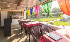 een restaurant met tafels en stoelen en uitzicht op een tuin bij Treebo Trend Lands End Beach Resort Morjim in Morjim