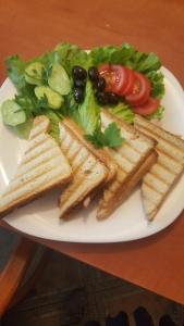 a white plate of food with a sandwich and salad at Cathedral Guesthouse in Varna City