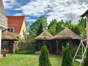 a gazebo with thatched roofs in a yard at Home Sweet Apartment in Bük