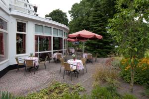 d'une terrasse avec des tables, des chaises et un parasol. dans l'établissement Fletcher Hotel Restaurant Veldenbos, à Nunspeet