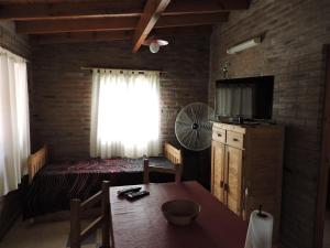 ein Schlafzimmer mit einem Bett, einem Fernseher und einem Tisch in der Unterkunft CABAÑAS LOS COCKERS in Villa General Belgrano