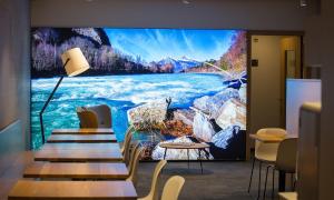 a large tv screen with a river on a wall at b_smart motel Landquart in Landquart