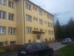 a yellow building with cars parked in front of it at Apartament Parkowy Rabka in Rabka-Zdrój