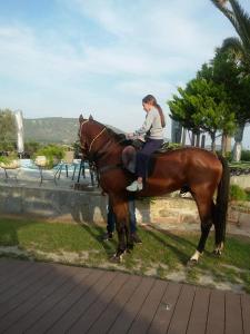 una mujer sentada sobre un caballo marrón en Ariadnes Holiday Accommodation I, en Apidias Lakos