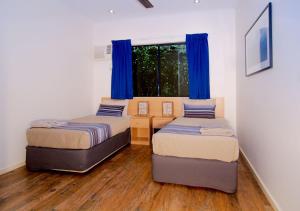 a bedroom with two beds and two windows at Cable Beach Apartments in Broome