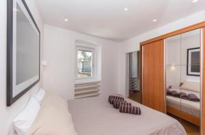 a white bedroom with a bed and a window at Appartment in center with parking in Pula