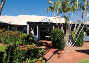 a white house with a tree in front of it at Cable Beach Apartments in Broome