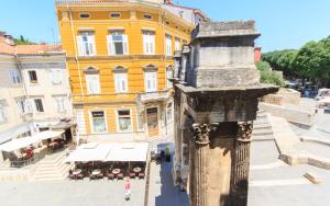 a tall yellow building with a column in front of it at Appartment in center with parking in Pula