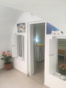 a white room with two mirrors and a table at Marcos Rooms in Oia