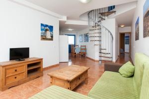 a living room with a couch and a tv and a table at TAO El Cotillo in El Cotillo