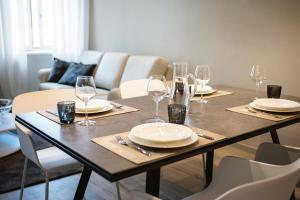 una mesa de comedor con platos y copas de vino en Cinquanta4 Charme Apartment en Trento