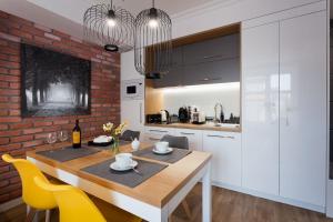 uma cozinha e sala de jantar com uma mesa de madeira e cadeiras amarelas em Silver Apartment Old Jewish Quarter em Cracóvia