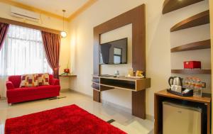 a living room with a red couch and a television at Zamzam Hotel and Convention Batu Powered By Archipelago in Batu