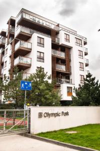 a white apartment building with a blue sign in front of it at Olympic Park in Kołobrzeg