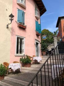 a pink building with tables and chairs in front of it at Locanda Agli Angeli in Gardone Riviera