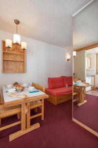ein Wohnzimmer mit einem roten Sofa und einem Tisch in der Unterkunft Résidence Pierre & Vacances Emeraude in Belle Plagne