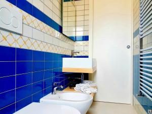 a blue tiled bathroom with a sink and a toilet at B&B All'ombra degli ulivi in Ostuni