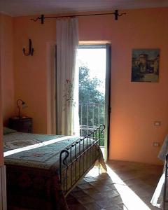 a bedroom with a bed and a large window at Agriturismo Il Vecchio Casale in Vatolla