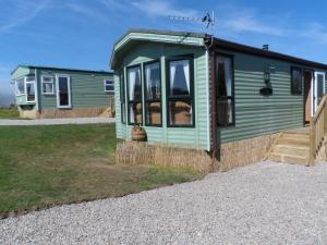 トゥルーロにあるLuxury Mobile Home near Perranporth situated on a quiet farmの砂利道の緑小屋