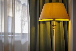 une lampe assise à côté d'une fenêtre avec rideau dans l'établissement Apart Hotel Vlad Tepes, à Braşov