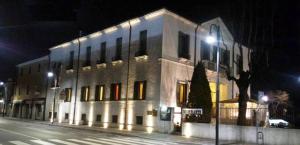 - un grand bâtiment blanc dans une rue de la ville la nuit dans l'établissement Hotel AB Baretta, à Legnaro