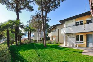 un edificio con palmeras y un patio de césped en Villa Cristina, en Lignano Sabbiadoro