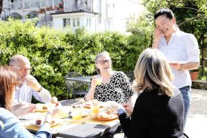 un grupo de personas sentadas alrededor de una mesa comiendo comida en A Casa Dei Nonni, en Ravello