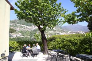 un grupo de personas sentadas en una mesa bajo un árbol en A Casa Dei Nonni, en Ravello