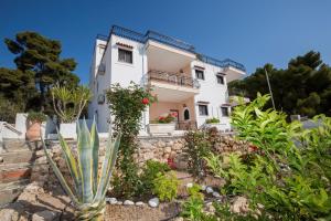 una casa blanca con plantas delante en Pefkides Aegina Boutique Apartments, en Agia Marina Aegina