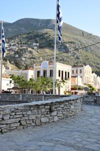 a stone wall with two flags in front of a building at Myrtia in Symi