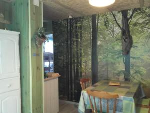 a dining room with a table and a forest mural on the wall at Le Nid D'Hirondelles in Donges