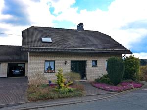 een stenen huis met een zwart dak op een straat bij Apartment in Deifeld with garden in Medebach