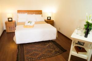 een slaapkamer met een bed en twee nachtkastjes en een tafel bij Suite 1-B El Rincón Garden House, Welcome To San Angel in Mexico-Stad