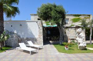 a house with two chairs and a dog sitting in the yard at A casa di Lina in San Foca