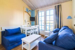 ein Wohnzimmer mit einem blauen Sofa und einem Tisch in der Unterkunft Residence Port Bourgenay - maeva Home in Talmont
